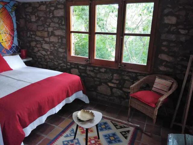 een slaapkamer met een bed, een stoel en ramen bij Hostal La vall in Sant Pau de Seguries