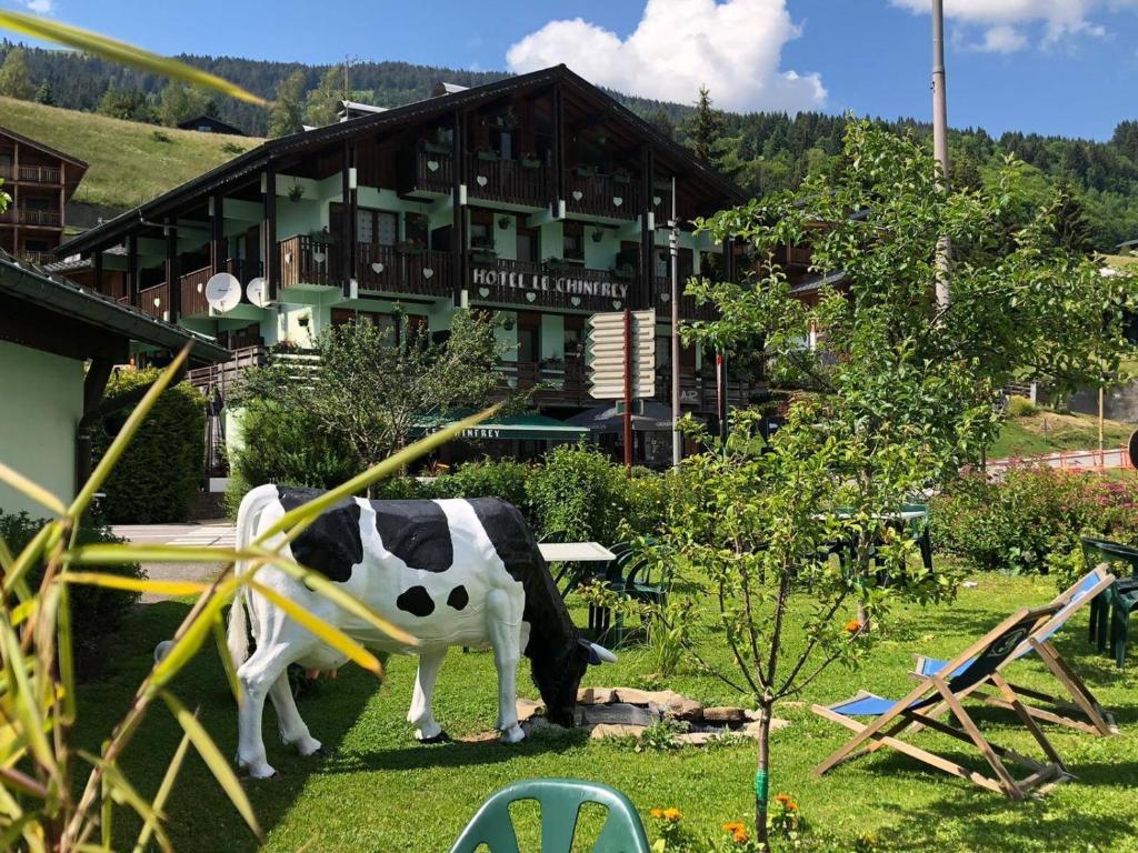 a statue of a cow in a yard with a building at Hôtel Le Chinfrey in Les Gets