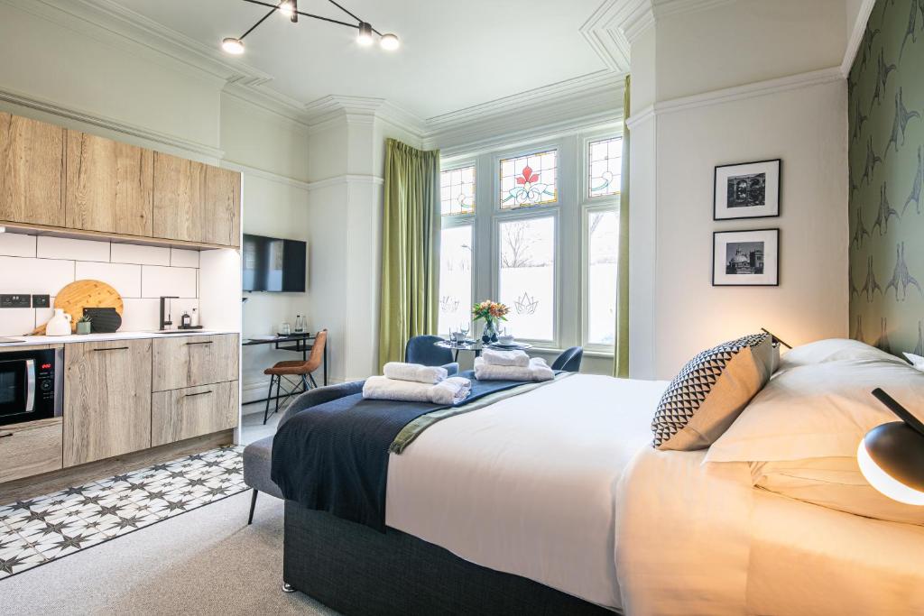 a bedroom with a large bed and a kitchen at The Belmont - Harrogate Stays in Harrogate