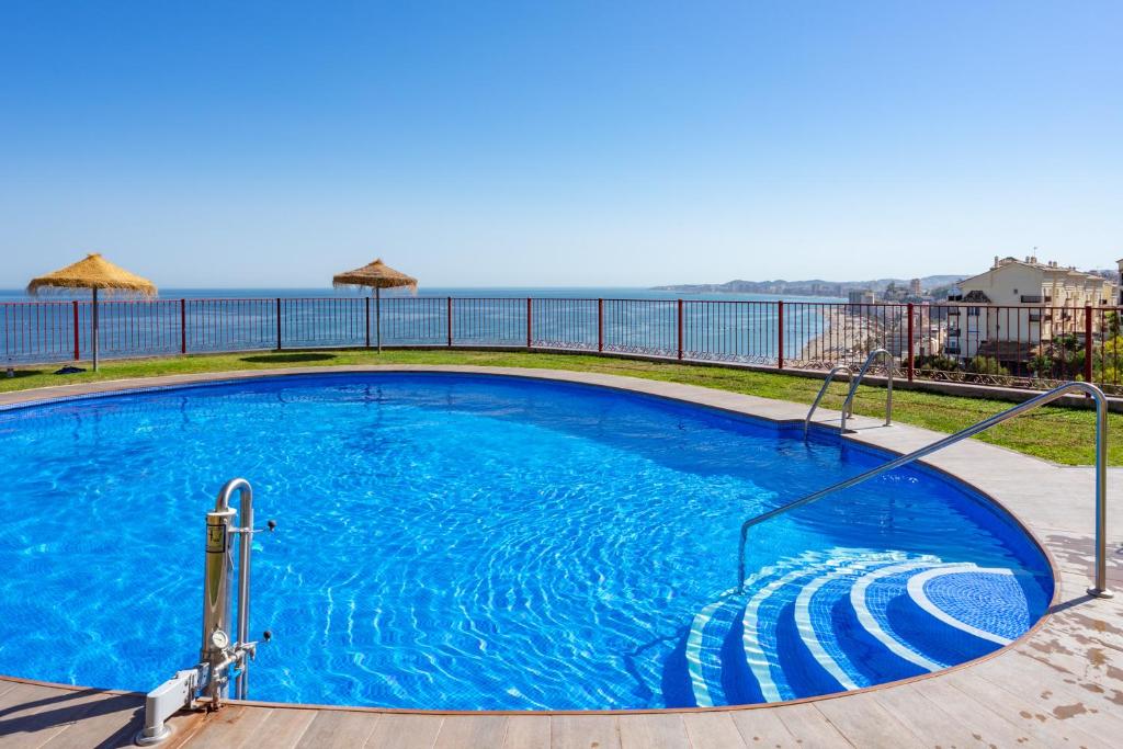 Seaview terrace with pool in Carvajal Ref 103 في Torremuelle: حمام سباحة أزرق كبير مع المحيط في الخلفية