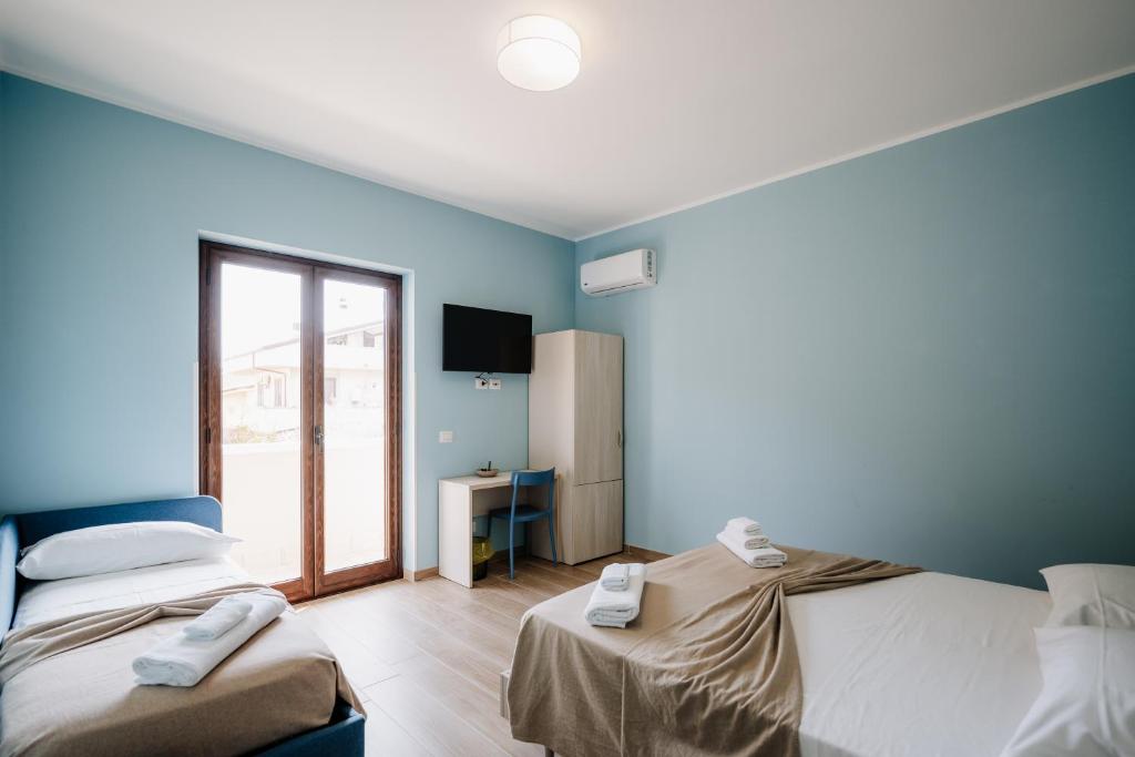 two beds in a room with blue walls at Campanella Rooms in Locri