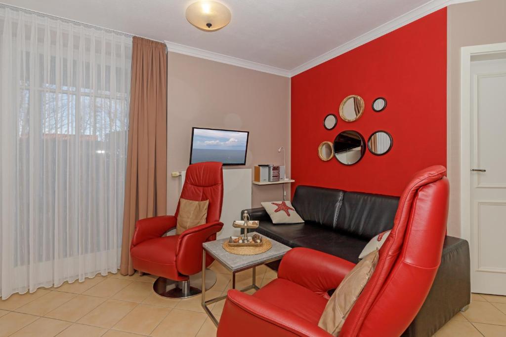 sala de estar roja con sillas rojas y TV en Dünenschloss Dünenschloss 2-05 en Kühlungsborn