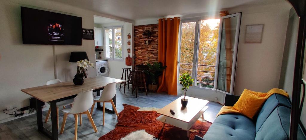 a living room with a blue couch and a table at Appartement lumineux cosy et calme proche du métro in Créteil