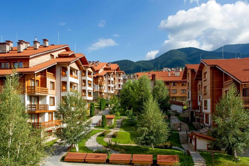 a group of apartment buildings in a town with trees at Cozy studio with balcony in 4-star hotel Saint Ivan Rilski, Bansko in Bansko