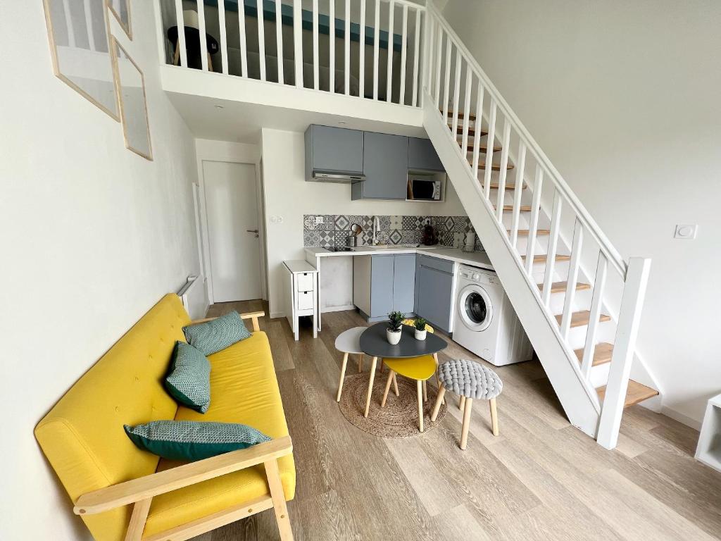 ein Wohnzimmer mit einem gelben Sofa und einem Tisch in der Unterkunft Le Petit Canada - Proche ville in La Rochelle