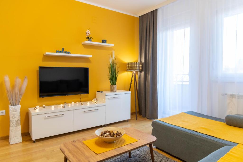 un soggiorno con TV su una parete gialla di Apartman Exclusive a Obrenovac