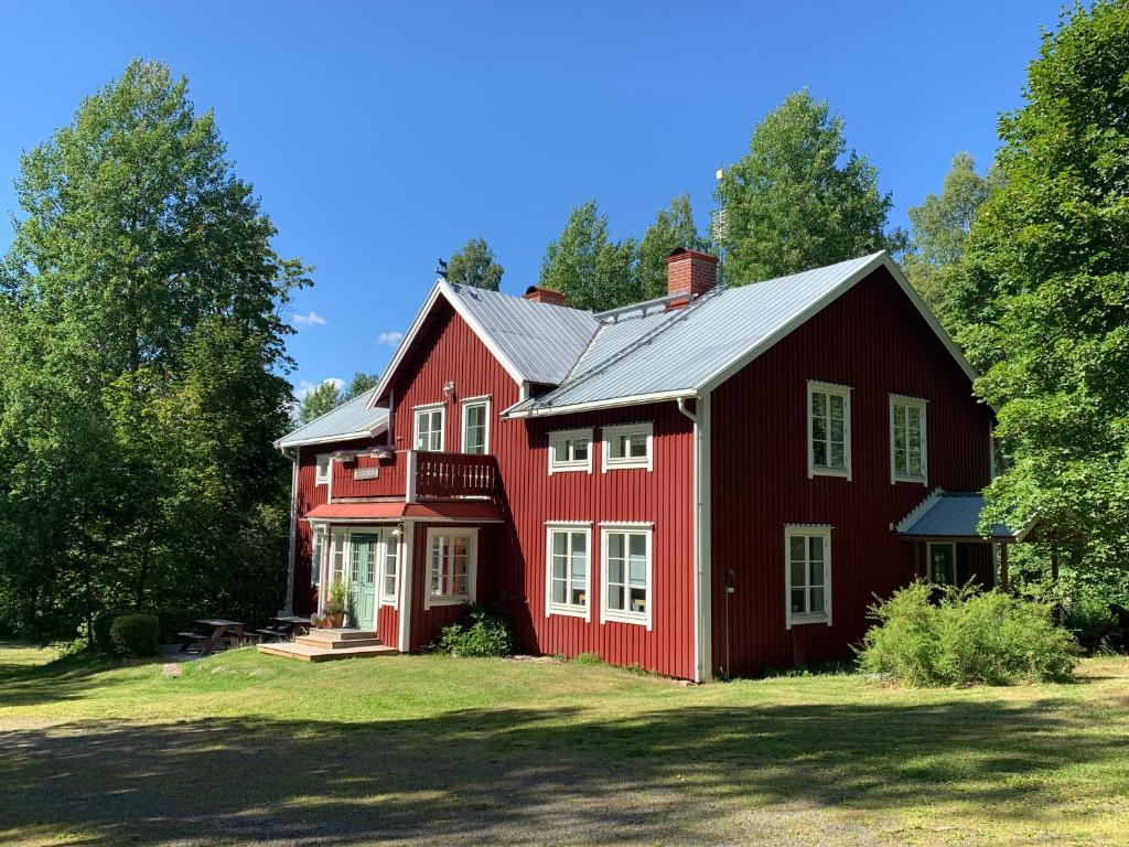 a red barn with white windows and a roof at Villa Skuleskogen in Docksta
