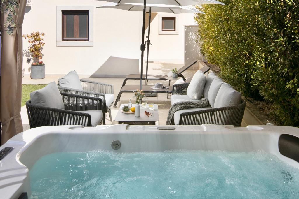 a hot tub in a yard with chairs and an umbrella at House NoE- with hot tub in Bale