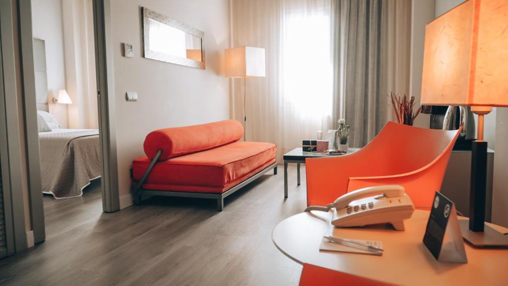 Habitación de hotel con silla roja y escritorio en Vértice Sevilla Aljarafe en Bormujos