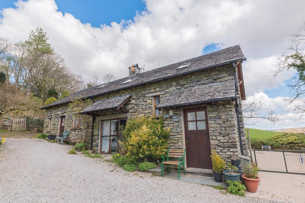 a stone house with a dog on top of it at Byre & Millers Woodland Coniston Sleeps 12 in Torver