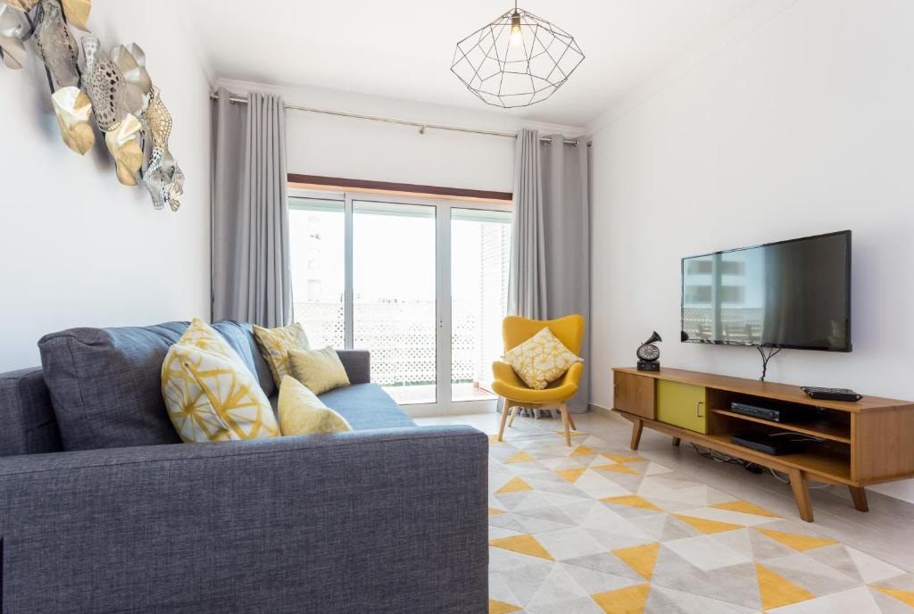 波爾蒂芒的住宿－Solemar - 2Pools - WIFI 500MBps - AC - Portimão，客厅配有蓝色的沙发和电视