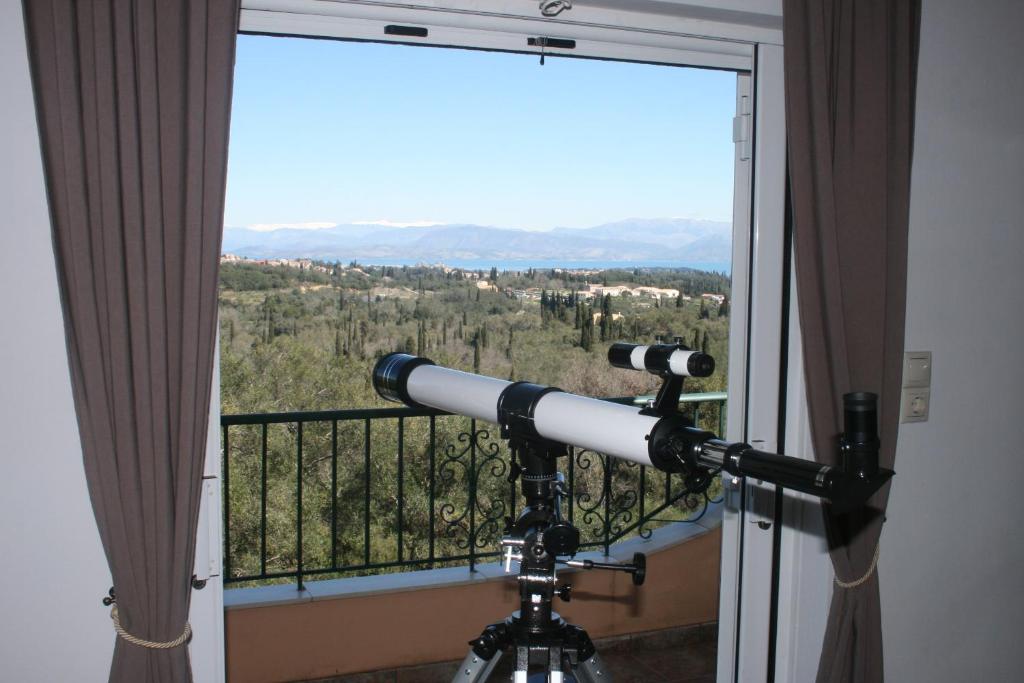 a telescope in front of a window with a view at Corfu Quality Suite, Tranquility, Mountain & Sea Views in Agios Gordios