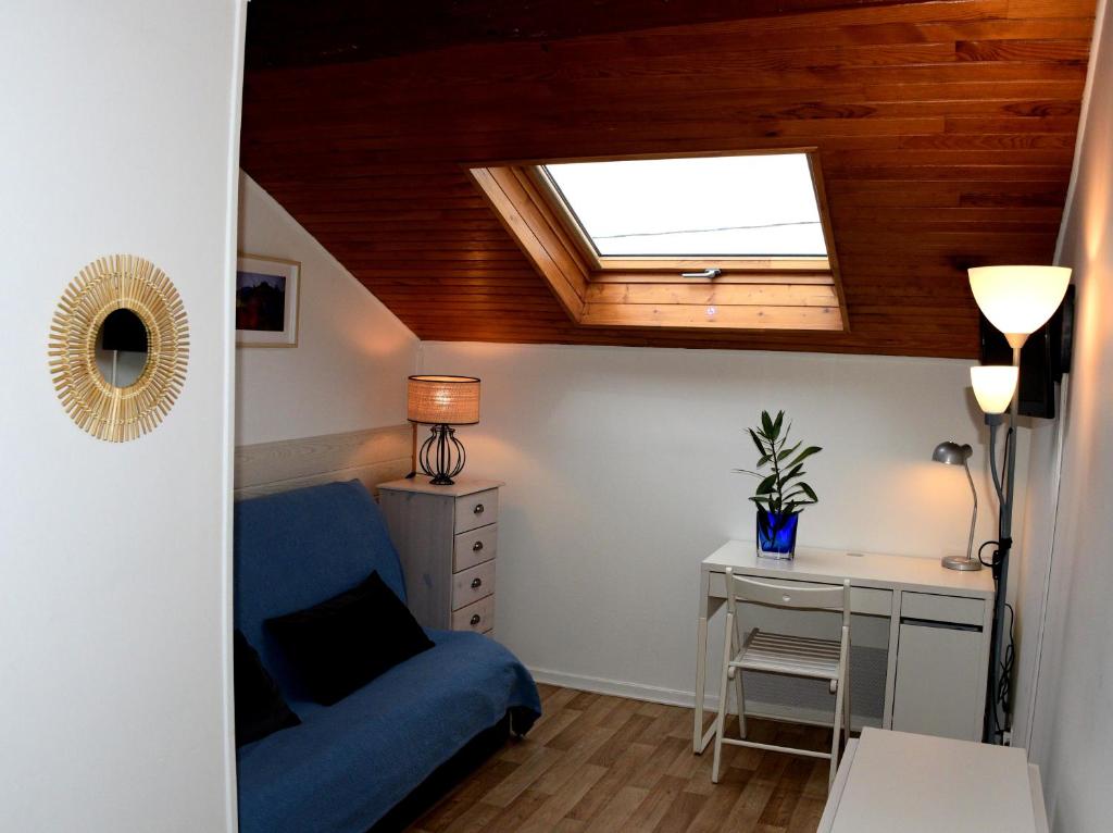 Habitación con sofá azul, escritorio y ventana. en Apartment Gîte Luvain Toulouse, en Toulouse