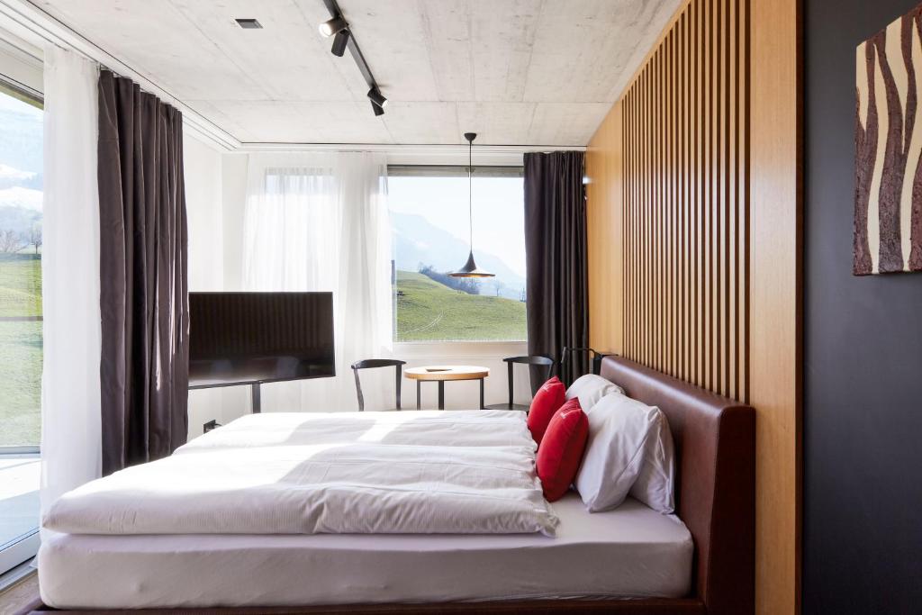 a bedroom with a large bed with a large window at Tailormade Hotel RIGIBLICK Küssnacht in Küssnacht