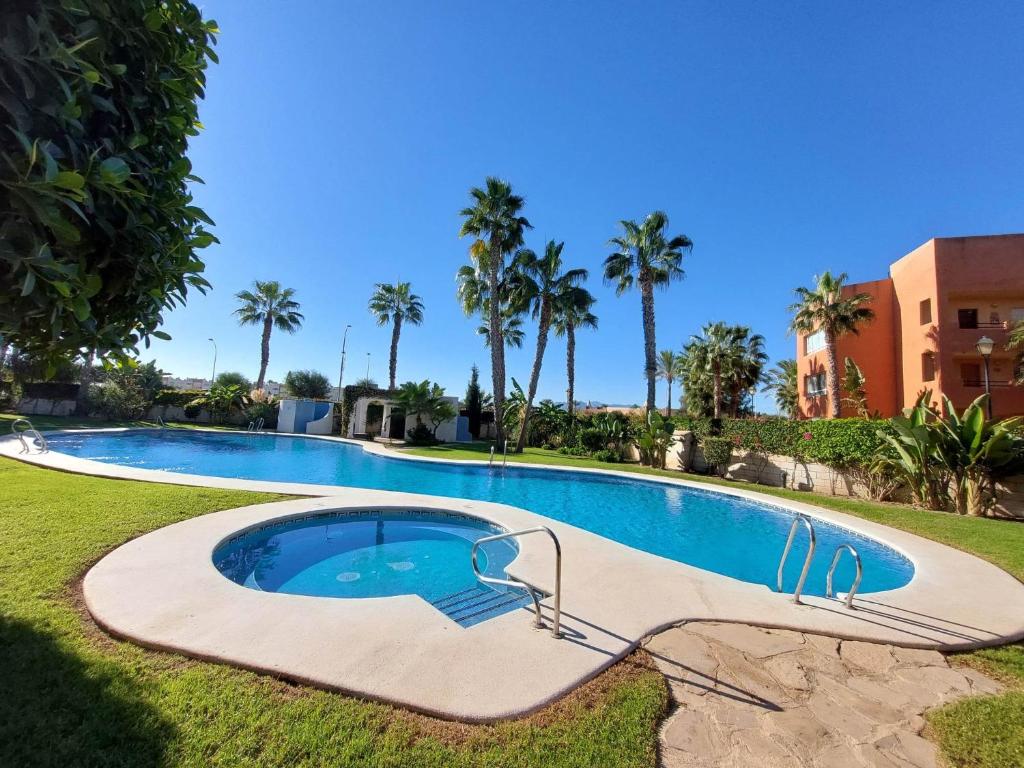 a large swimming pool in a yard with palm trees at Casa Verso Vera Playa in Vera