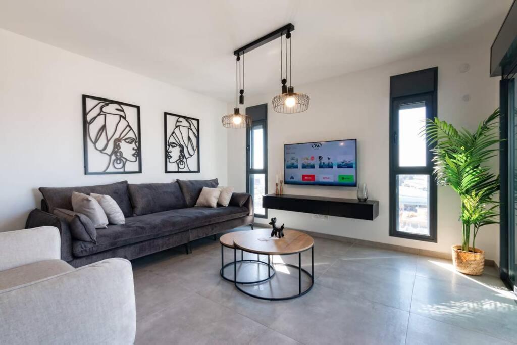 een woonkamer met een bank en een tafel bij O&O Group - Luxury APT/3 BR/New Tower/Parking in Or Yehuda