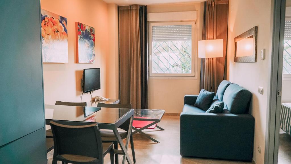 uma sala de estar com um sofá azul e uma mesa em Apartamentos Vértice Sevilla Aljarafe em Bormujos