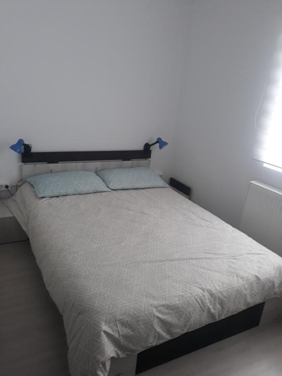 1 cama en un dormitorio con una pared blanca en Bellacasa en Zalău
