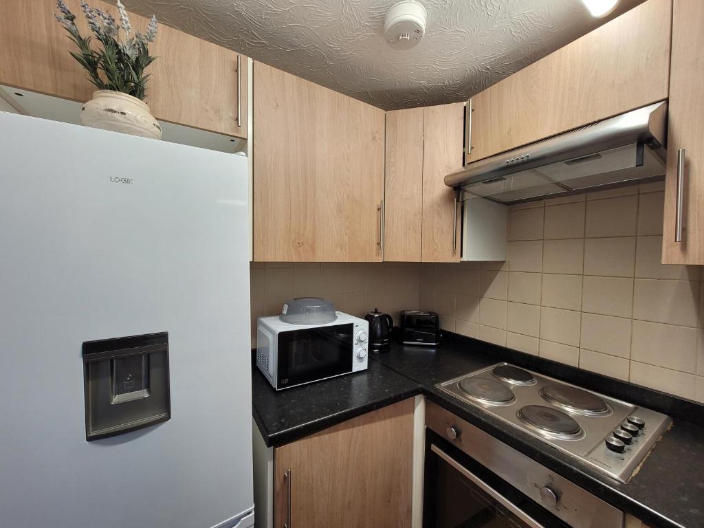 a small kitchen with a microwave and a stove at Tastefully decorated 1 bed flat near AbbeyWood in Belvedere