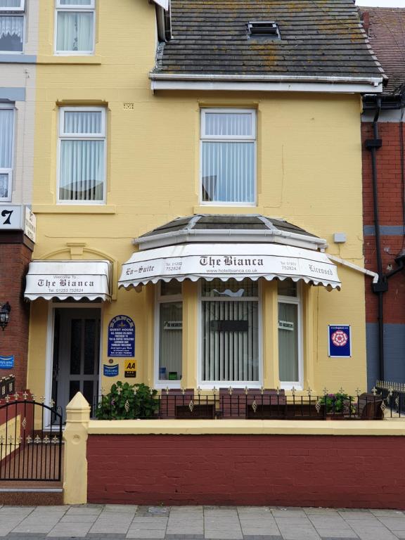 a yellow building with white awnings on it at Bianca Guesthouse in Blackpool