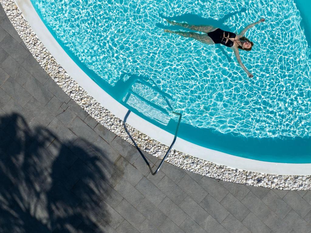 a man is swimming in a swimming pool at Amber Light Villas in Imerovigli