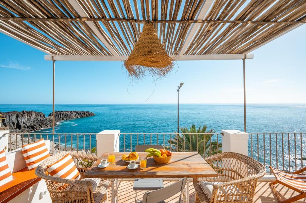 a table on a balcony with a view of the ocean at Casa da Rocha in Câmara de Lobos