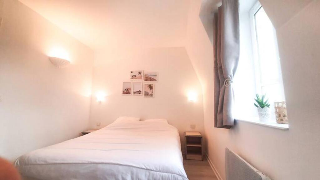 a small bedroom with a bed and a window at Appartement avec piscine, 100m plage et hypercentre in Cabourg