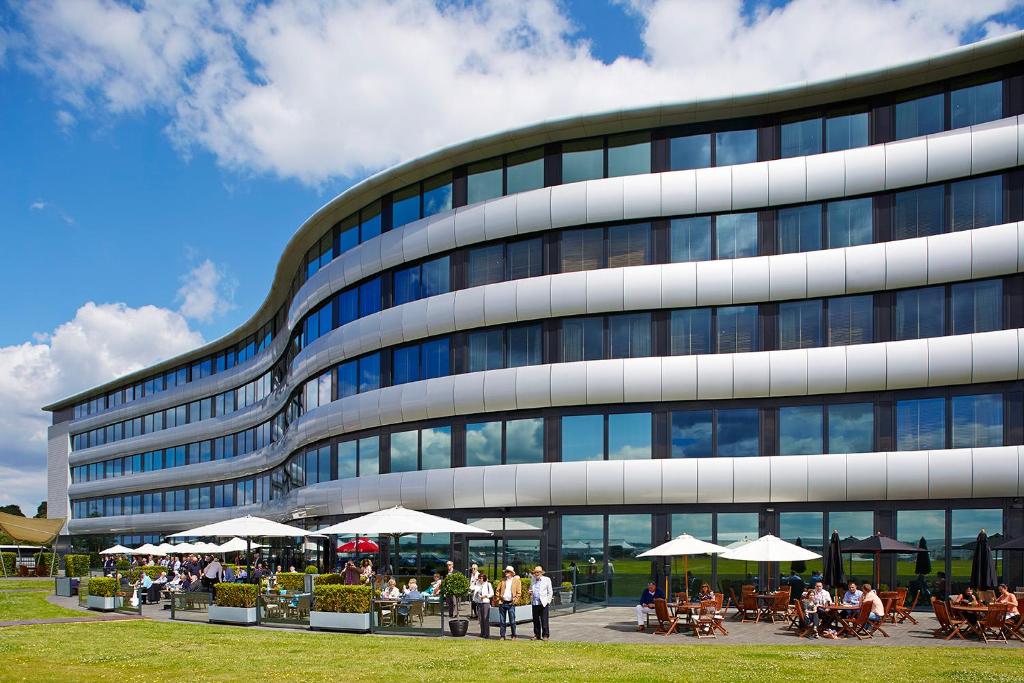 um edifício alto com pessoas sentadas fora dele em Aviator em Farnborough