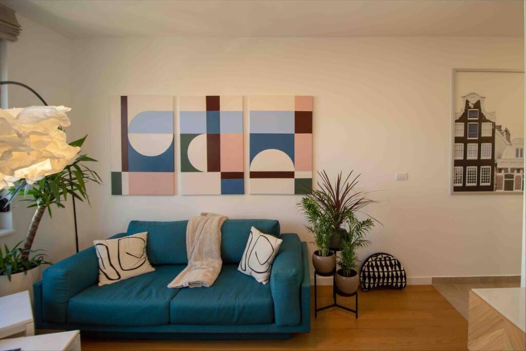 eine blaue Couch in einem Wohnzimmer mit einem Gemälde in der Unterkunft GARDOS BAUHAUS Apartment in Belgrad