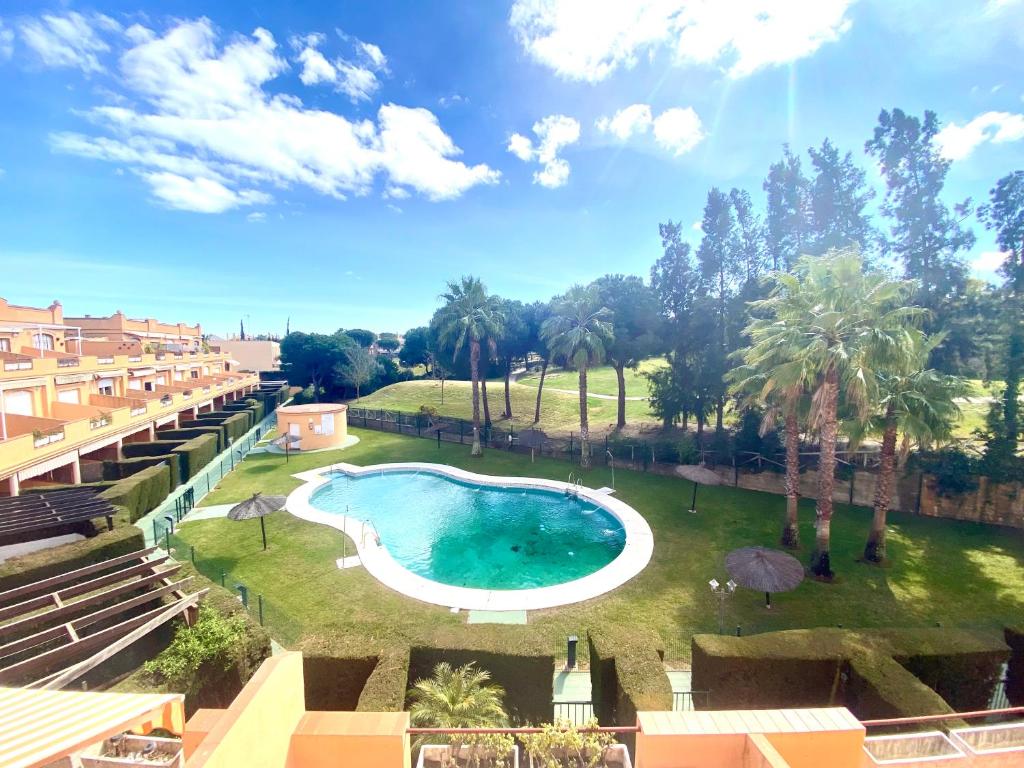 a swimming pool in a yard with palm trees at Ático Islantilla Golf in Islantilla