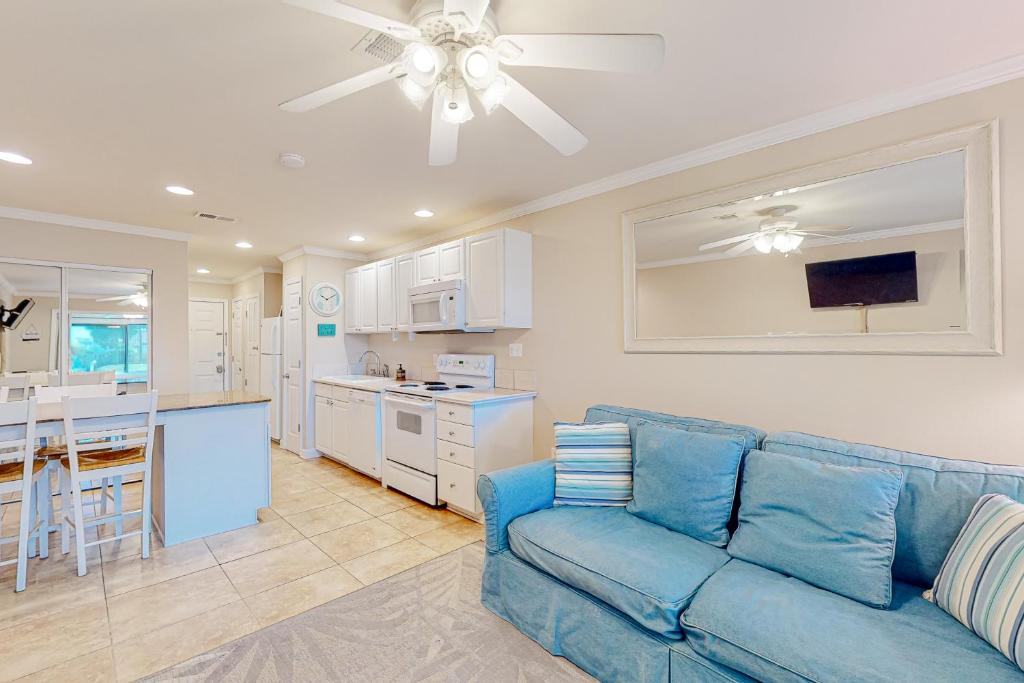 ein Wohnzimmer mit einem blauen Sofa und einer Küche in der Unterkunft Sunset Harbor Palms 2 102 Luzviminda Cove in Navarre