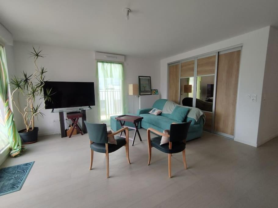 ein Wohnzimmer mit einem blauen Sofa und Stühlen in der Unterkunft Rueil-Malmaison appartement spacieux et calme in Rueil-Malmaison