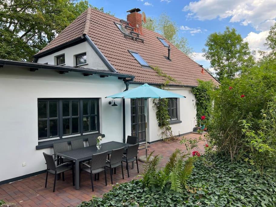ein Haus mit einem Tisch mit Stühlen und einem Sonnenschirm in der Unterkunft Ferienhaus Schlossstraße in Kühlungsborn