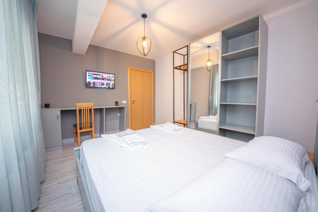 a bedroom with a large white bed and a desk at Aerial Hotel & Spa in Vlorë