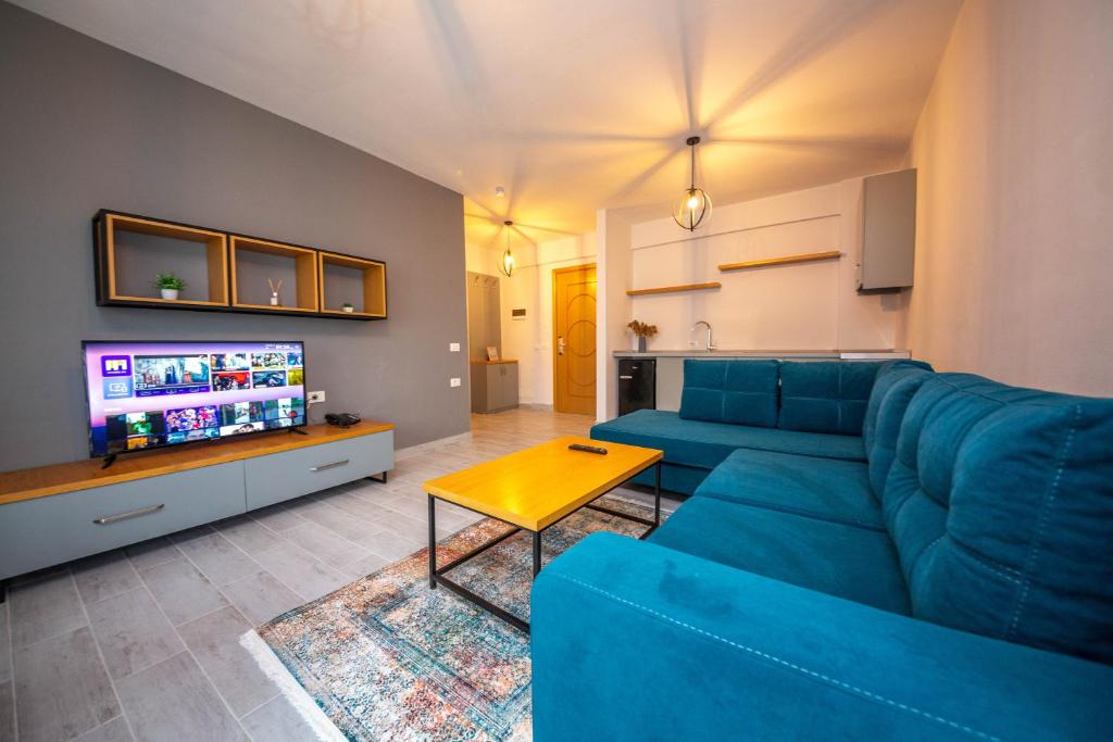 a living room with a blue couch and a tv at Aerial Hotel & Spa in Vlorë