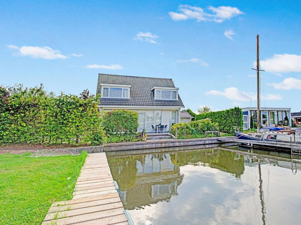 una casa con un barco en un canal en Detached house on the water with jetty in Langweer Frl, en Boornzwaag