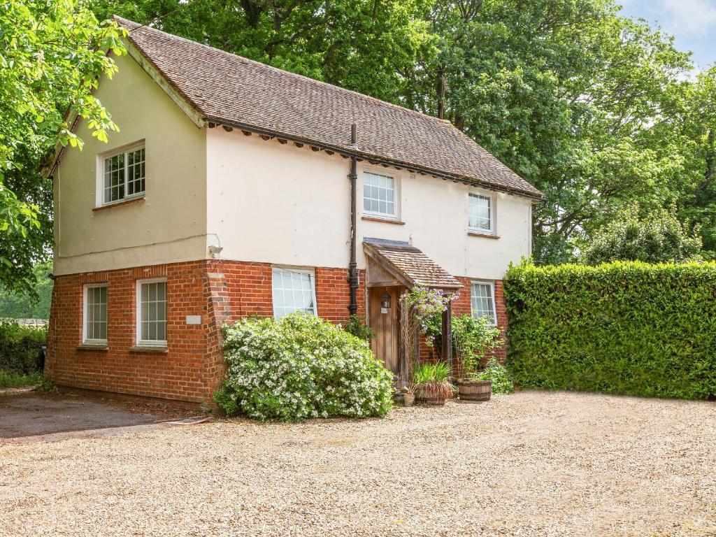 a white and red brick house with a hedge at Garden Cottage 1 - Uk42881 in Liphook