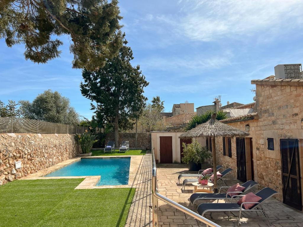 a backyard with a swimming pool and a stone wall at Villa Petita Llombards in Es Llombards