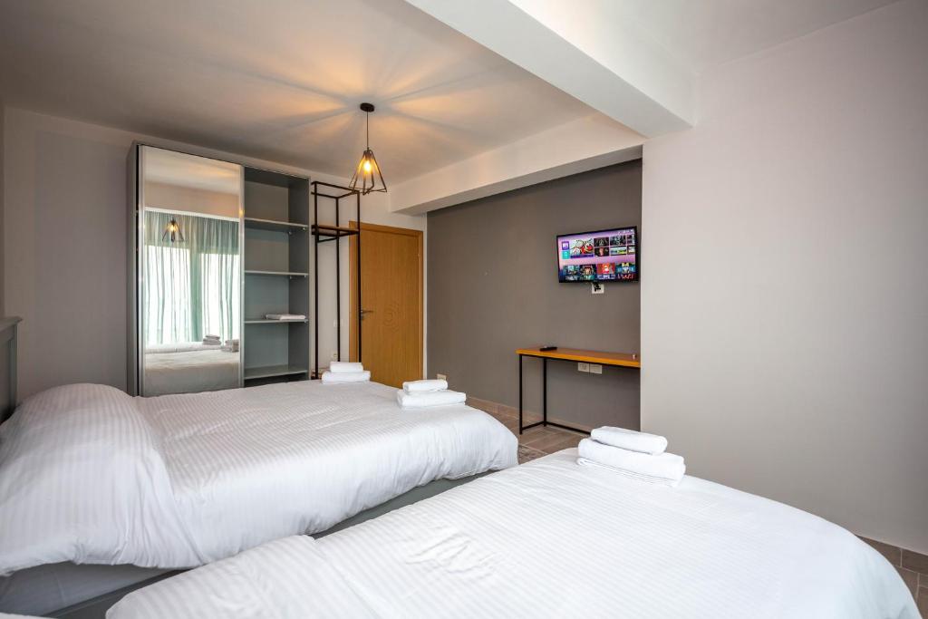 two beds in a bedroom with a tv on the wall at Aerial Hotel & Spa in Vlorë