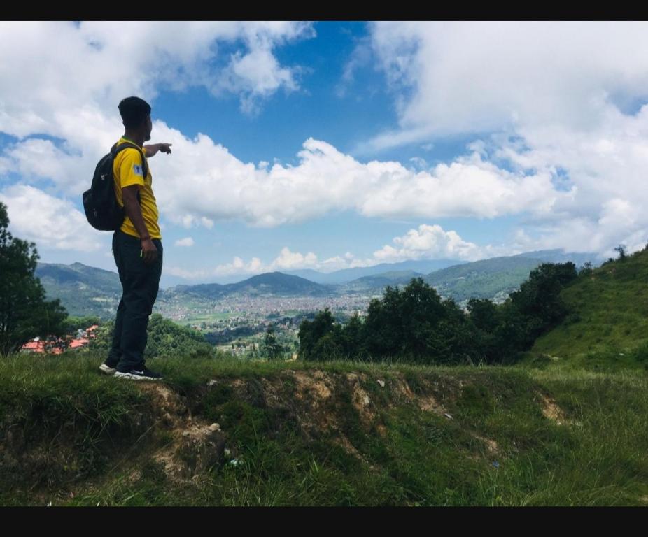 un hombre con una mochila de pie en la cima de una colina en COMMUNITY HOLIDAY INN en Panauti