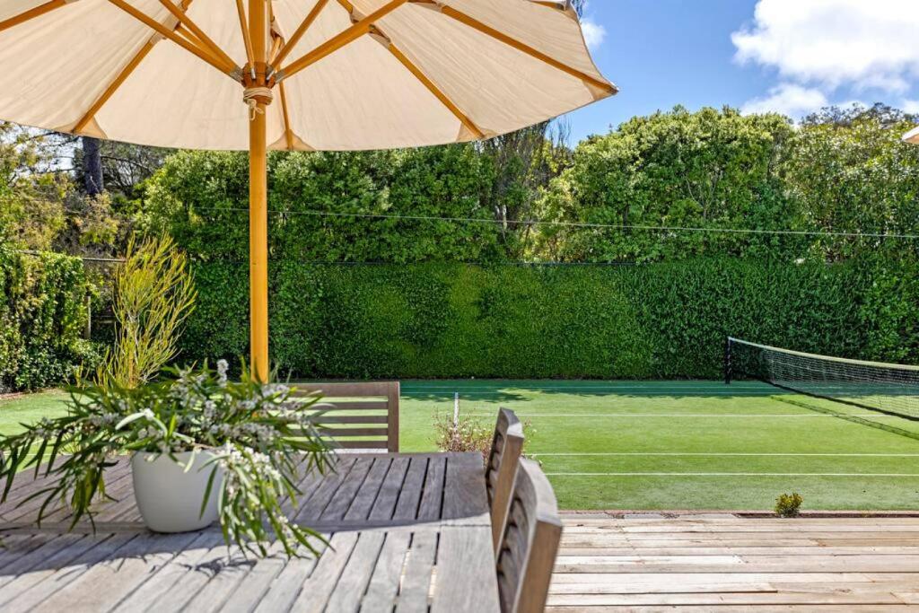 a patio with an umbrella and a tennis court at Coastal Cool -Pool, Tennis Court in Sorrento