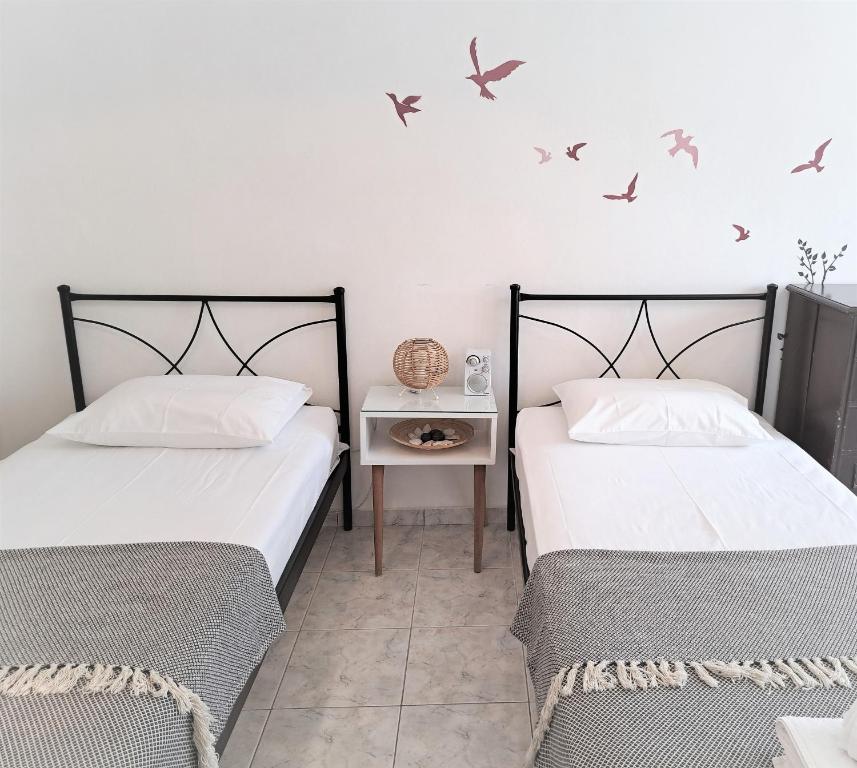 two beds in a room with birds on the wall at Ariadne Studio in Kyparissia