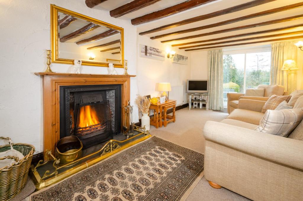 a living room with a fireplace and a couch at Nans, Elterwater in Chapel Stile