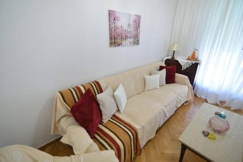 een woonkamer met een witte bank en rode kussens bij Το σπίτι μας in Athene
