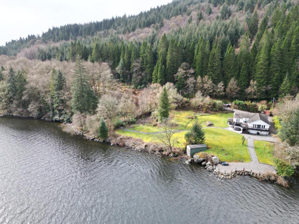 an aerial view of a house on the shore of a lake at WATERSIDE 3 BED COTTAGE, HOT TUB, SAUNA, PVT BEACH in Arrochar