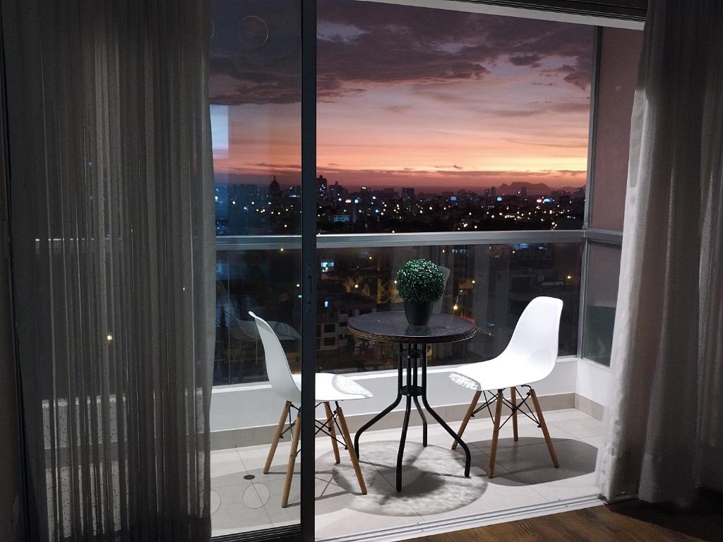 a balcony with a table and chairs in front of a window at Departamento BH South in Lima