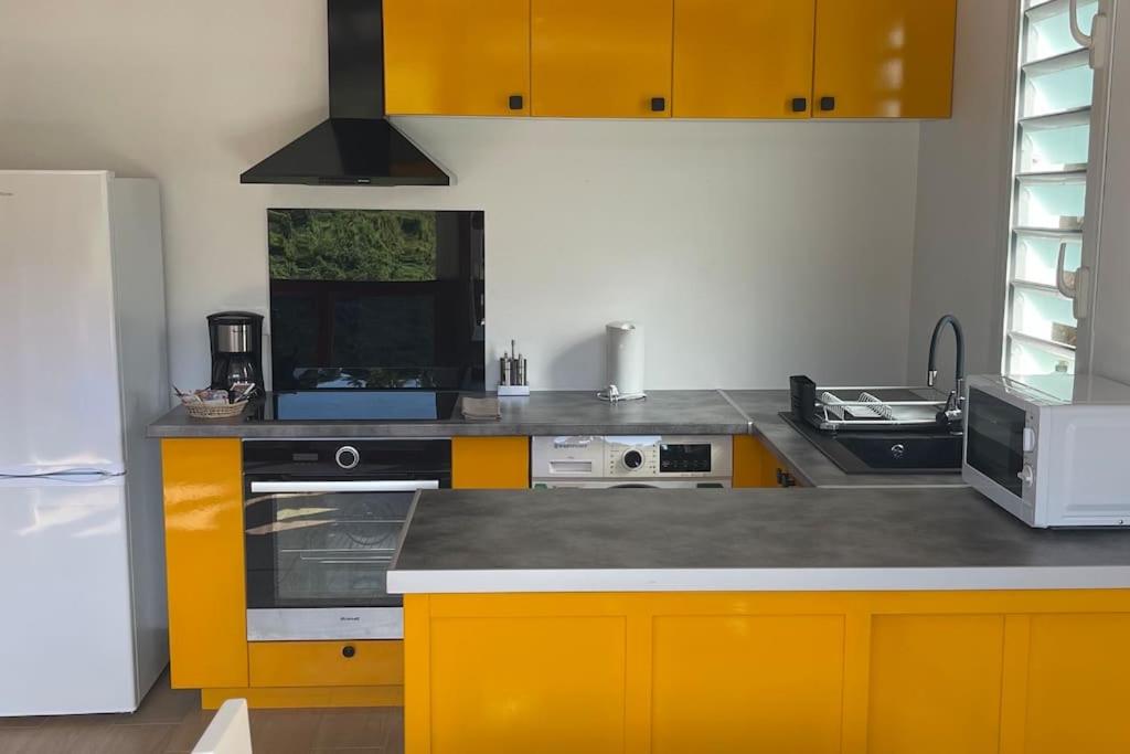 a kitchen with yellow cabinets and a stove top oven at Gites de la vallée in Le Gosier