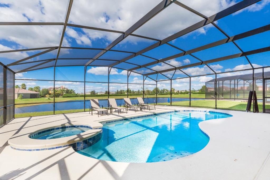 une grande piscine avec des chaises et un grand plafond en verre dans l'établissement Providence Luxurious 6 Bed Pool home, Lake View, Clubhouse, Resort Pool by Orlando Holiday Rental Homes LLC 2281, à Davenport