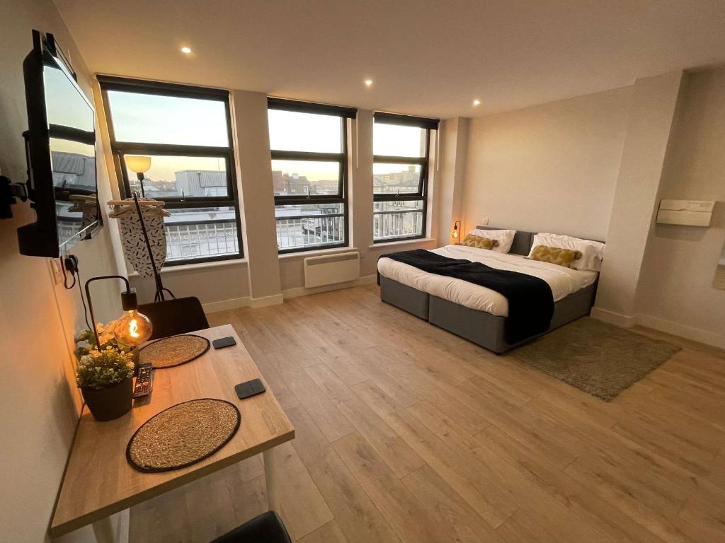 a bedroom with a bed and a table and windows at Market-Side King Bed Suite in Northampton