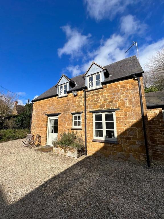 a brick house sitting on top of a gravel driveway at Delightful Pretty Cottage in Banbury